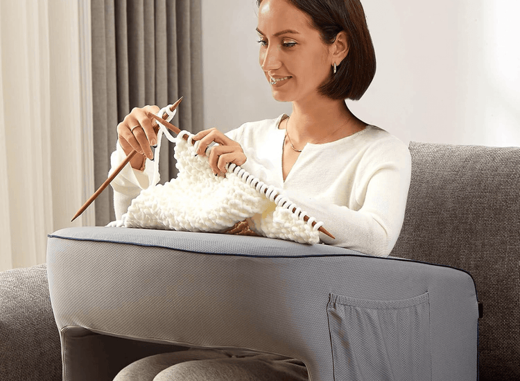 Woman knitting, pillow on her lap